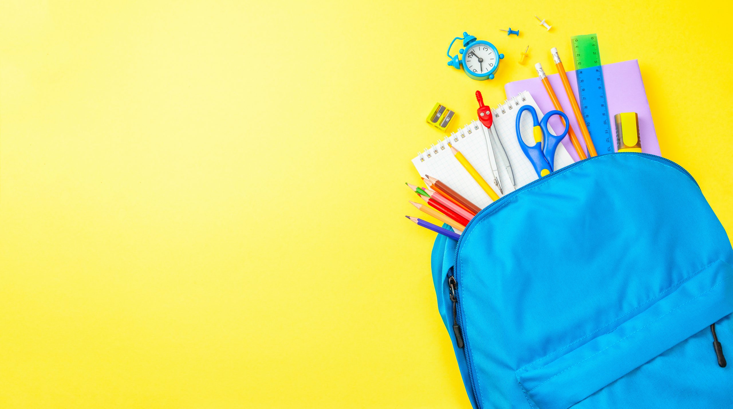 Back to school. School bag with supplies for school on yellow background.